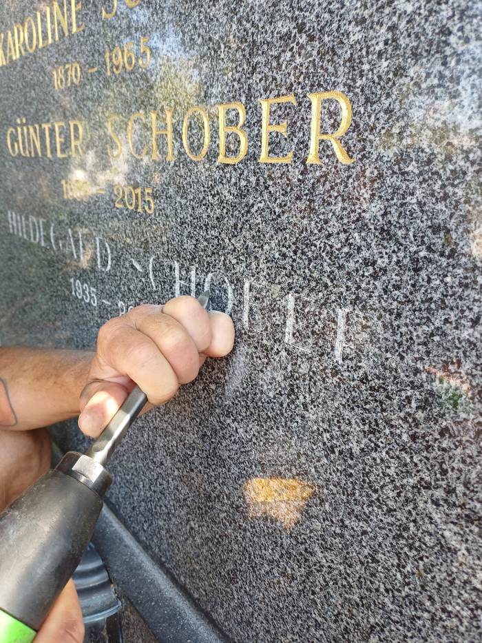 Steinmetz graviert eine Inschrift mit einem Luftdruckmeißel am Zentralfriedhof
