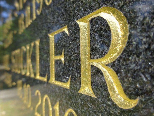 Vergoldete Inschrift auf dunklem Granit in Nahaufnahme