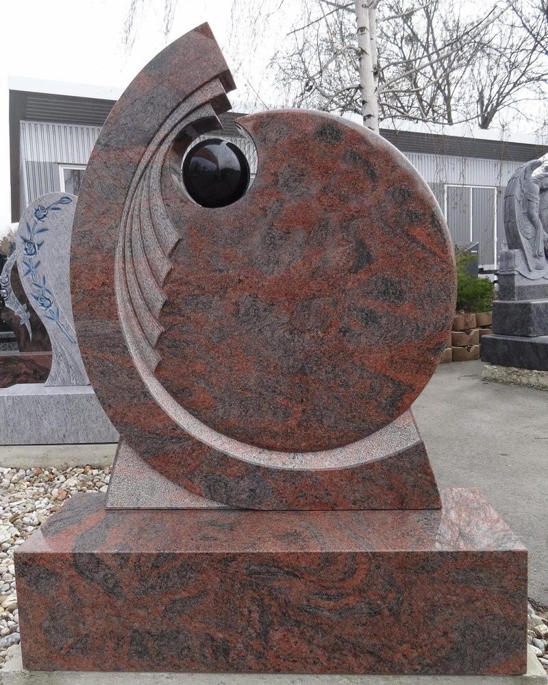 Moderner Grabstein aus rotem Multicolor-Granit in Kreisform mit eingesetzter schwarzer Granitkugel, mit Stufe